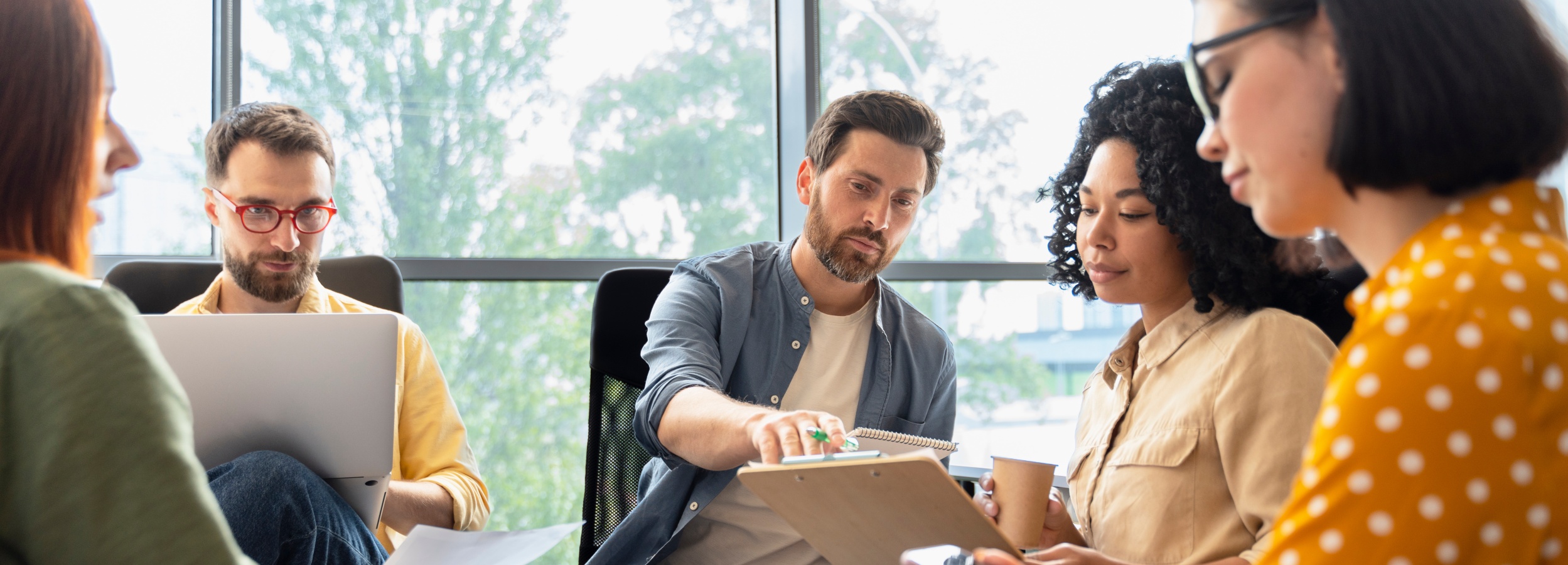 Team von Geschäftsleuten sitzt in einem modernen Büro in einer Diskussion zusammen.